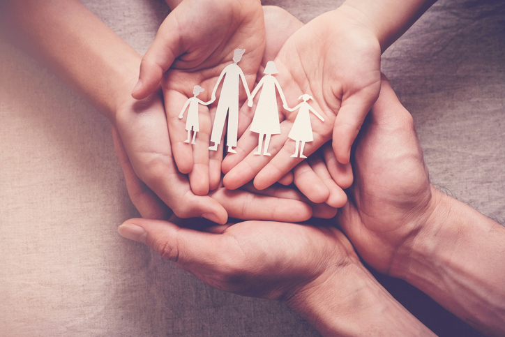 Adult and children hands holding paper family cutout, family home, foster care, homeless charity support concept